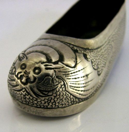 An antique Chinese export silver novelty pin cushion formed in the shape of a traditional slipper, featuring chased bat motifs and textured surface decoration. View II