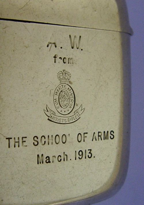 An Edwardian sterling silver vesta case featuring engraved military crests, text reading THE SCHOOL OF ARMS March. 1913, a side attachment ring, and a hinged lid. View III
