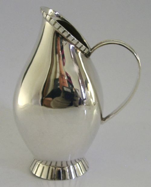 A pear-shaped mid-century sterling silver cream jug featuring a fluted rim, a matching fluted foot ring, and a single loop handle. View II