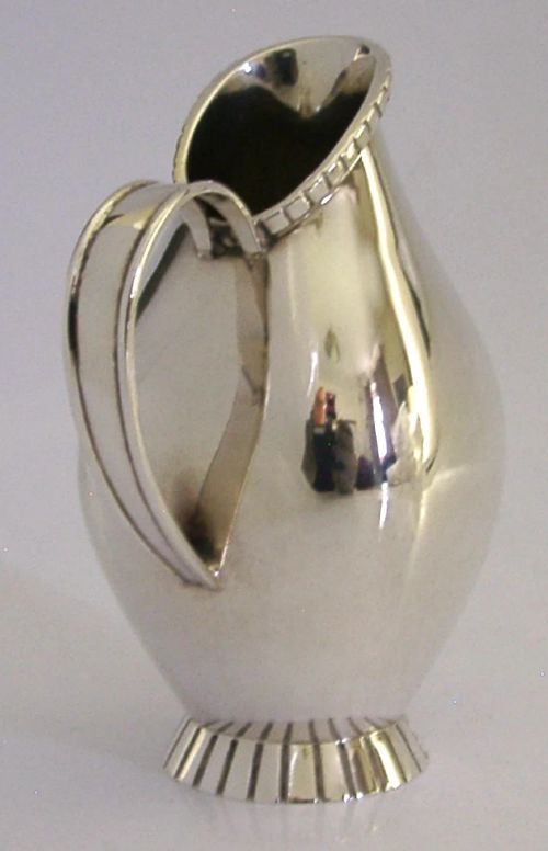 A pear-shaped mid-century sterling silver cream jug featuring a fluted rim, a matching fluted foot ring, and a single loop handle. View V