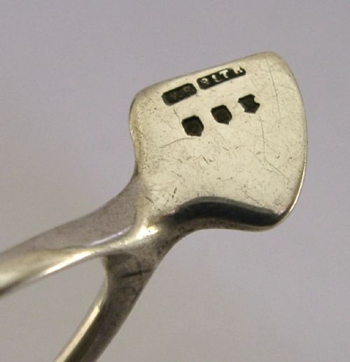A pair of solid sterling silver sugar tongs shaped like a bird wishbone with visible British hallmarks on the upper bridge. View VI