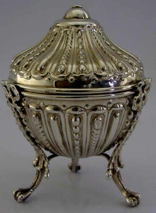 A Victorian sterling silver string box featuring detailed repousse fluting, a domed lid, and three ornate scrolled feet. View IV