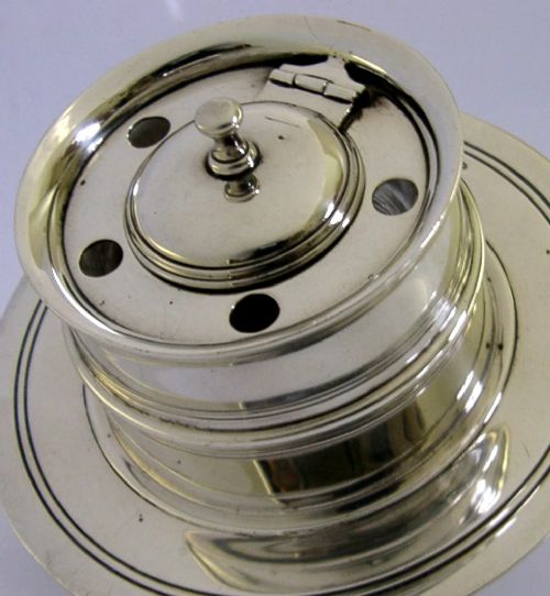 A solid sterling silver circular capstan inkwell featuring a hinged central lid and pierced quill holes set upon a wide dished base with visible hallmarks. View III