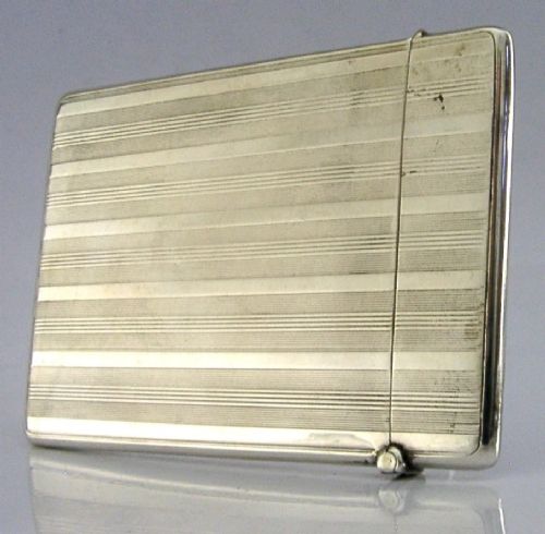 An open rectangular sterling silver card case with linear engine-turned patterns and a central circular monogrammed cartouche. View VI