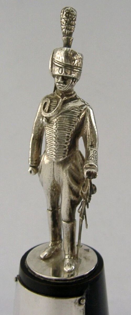 A sterling silver figurine depicting a Royal Hussar soldier in full military dress uniform, standing atop a tapered black wooden plinth with a silver presentation plaque. View III