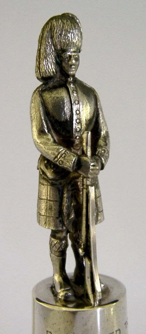 A polished sterling silver table bell topped with a sculpted Black Watch soldier figurine and featuring engraved regimental lettering on the bell body. View III
