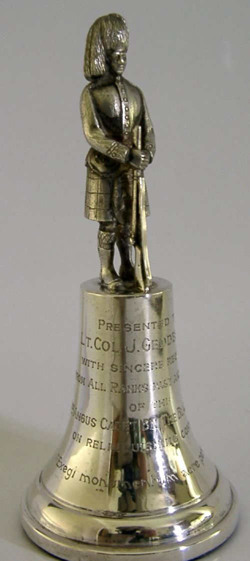 A polished sterling silver table bell topped with a sculpted Black Watch soldier figurine and featuring engraved regimental lettering on the bell body. View V
