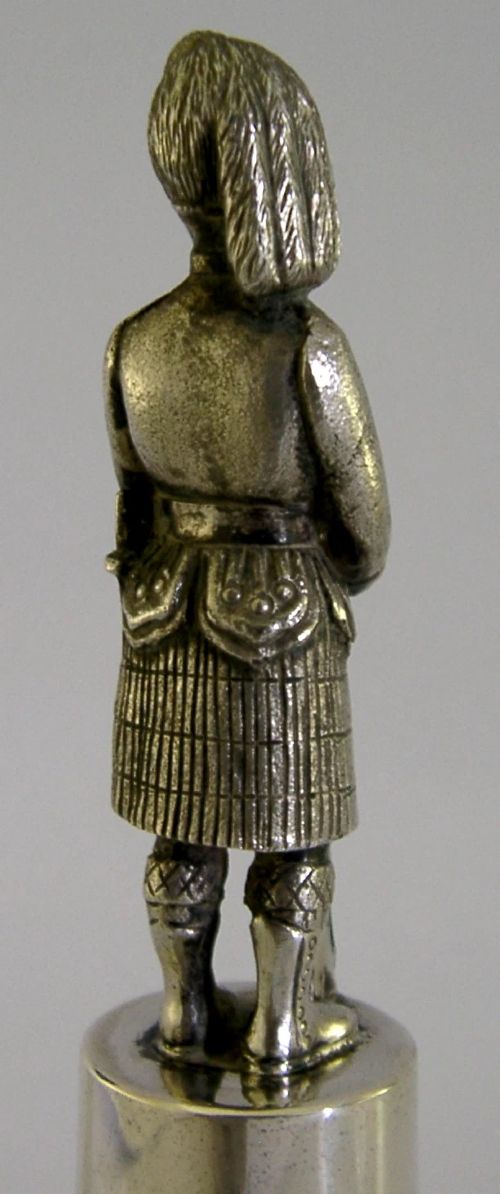 A polished sterling silver table bell topped with a sculpted Black Watch soldier figurine and featuring engraved regimental lettering on the bell body. View VIII
