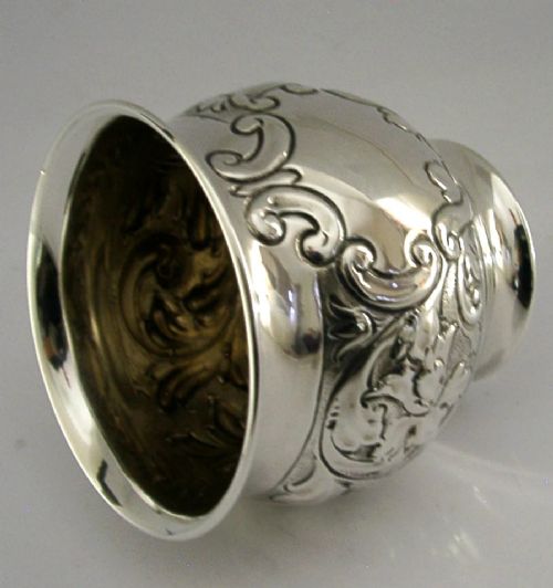 An Edwardian sterling silver fern pot featuring detailed embossed acanthus leaf and scroll decoration around the body with a polished flared rim. View V