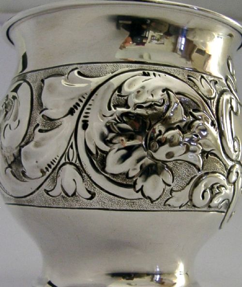 An Edwardian sterling silver fern pot featuring detailed embossed acanthus leaf and scroll decoration around the body with a polished flared rim. View IX
