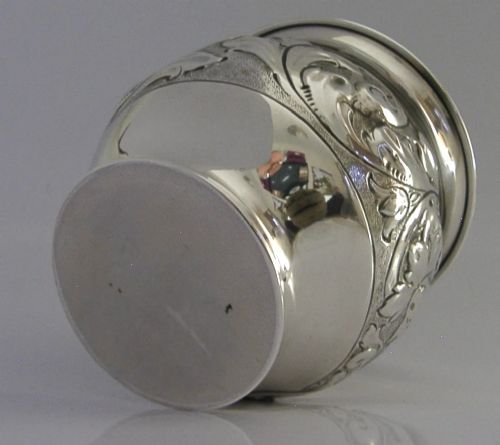 An Edwardian sterling silver fern pot featuring detailed embossed acanthus leaf and scroll decoration around the body with a polished flared rim. View X