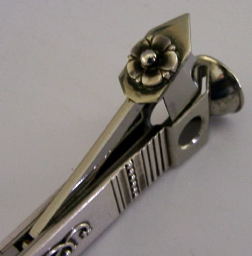 A mid-century sterling silver cigar cutter featuring a textured casing with a raised scroll motif and a stainless steel cutting blade. View IV