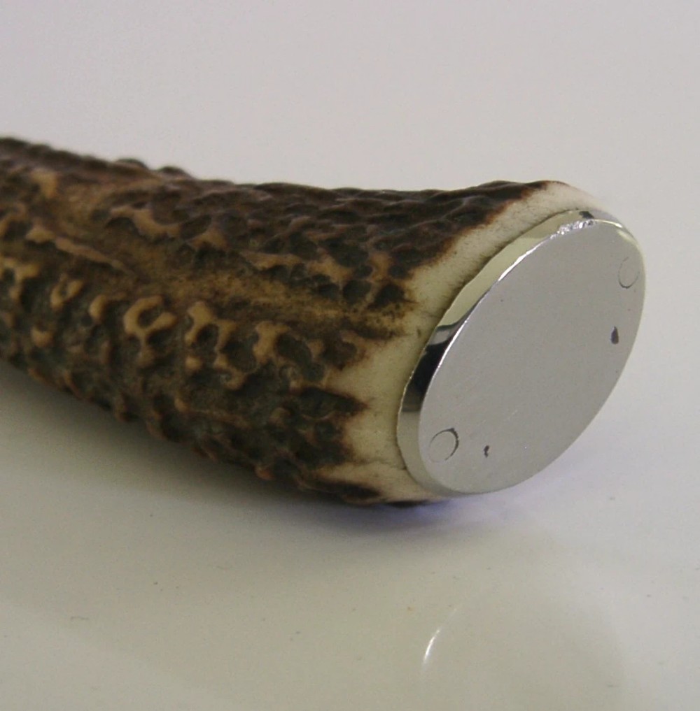 An Edwardian sterling silver cheese knife featuring a curved silver blade with hallmarks and a dark brown textured stag antler handle. View VII