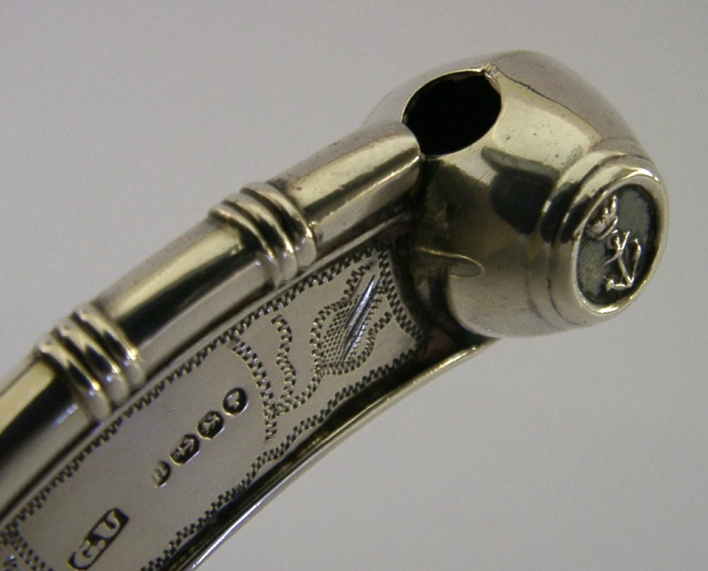 A Victorian sterling silver boatswains whistle featuring bright-cut engraving, British silver hallmarks, and a crowned anchor emblem on the spherical buoy. View V