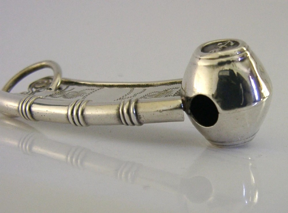 A Victorian sterling silver boatswains whistle featuring bright-cut engraving, British silver hallmarks, and a crowned anchor emblem on the spherical buoy. View IX