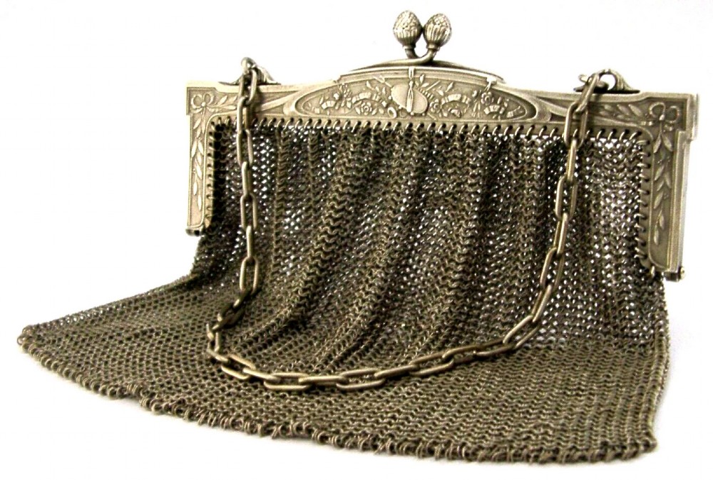 An antique French solid silver chain link mesh purse featuring an ornate Art Nouveau carved frame with a pinecone clasp.