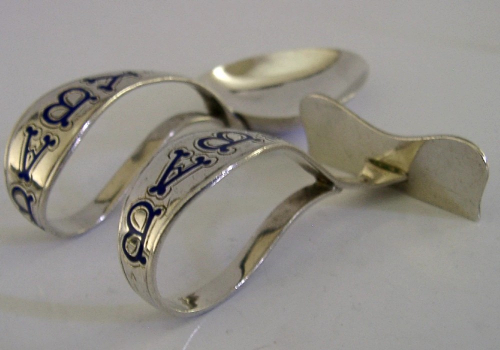 A sterling silver spoon and pusher set featuring blue enamel lettering inside an open black presentation box with white silk lining. View IV