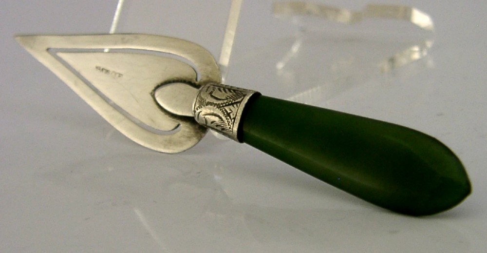 An Edwardian sterling silver trowel-shaped bookmark featuring a cutout page clip and a smooth dark green jade handle.