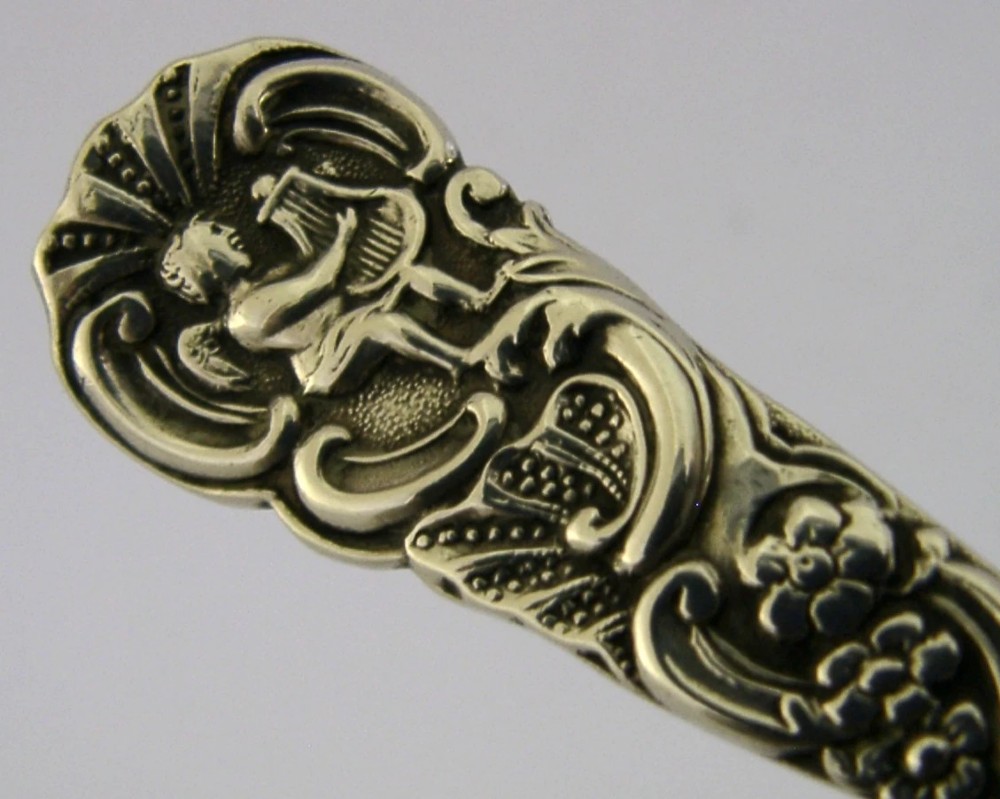 An Edwardian sterling silver tea caddy spoon with a smooth ovate bowl and an embossed handle depicting an angel holding a harp. View V