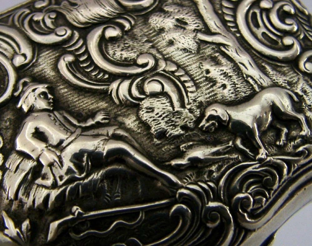 An antique rectangular silver box with intricate repousse scrollwork depicting a hunter seated beside a hound in a woodland setting. View II
