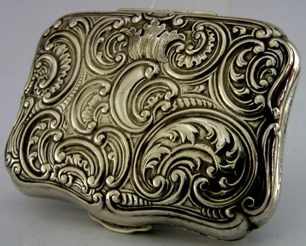 An antique rectangular silver box with intricate repousse scrollwork depicting a hunter seated beside a hound in a woodland setting. View IV