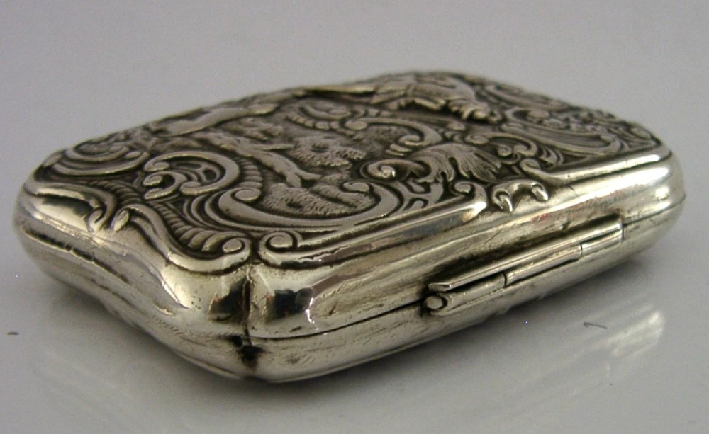 An antique rectangular silver box with intricate repousse scrollwork depicting a hunter seated beside a hound in a woodland setting. View VI