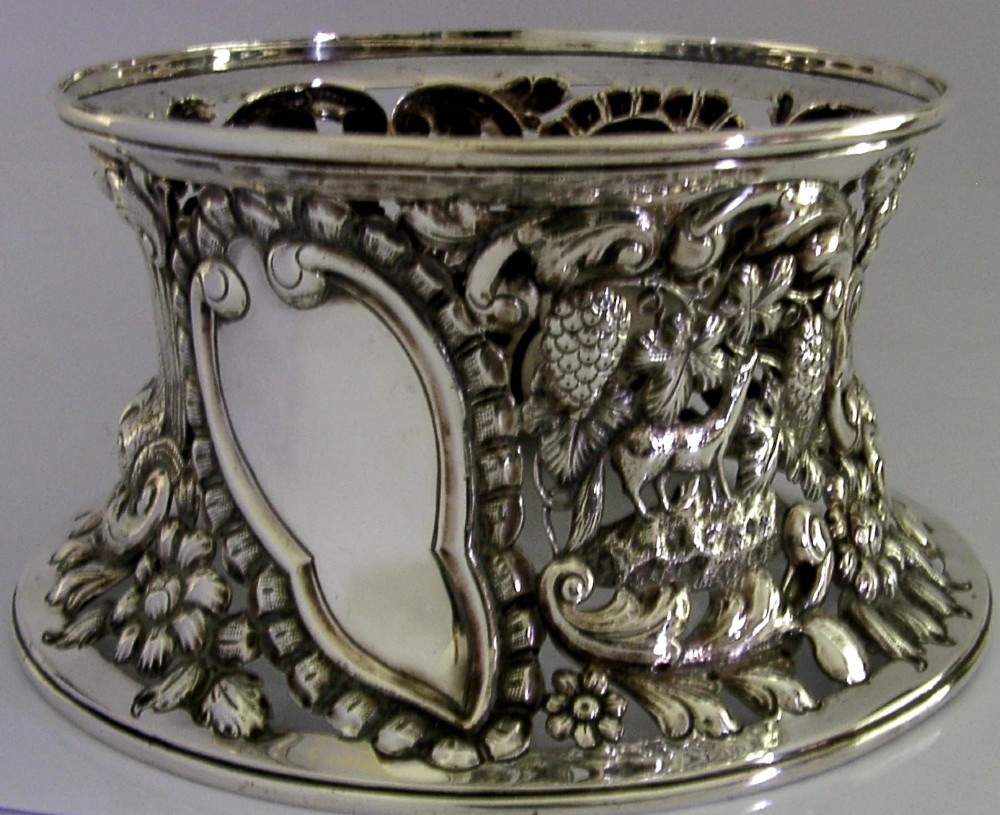An hourglass-shaped sterling silver dish ring featuring intricately pierced fretwork with floral motifs, scrolls, and marine life details. View III