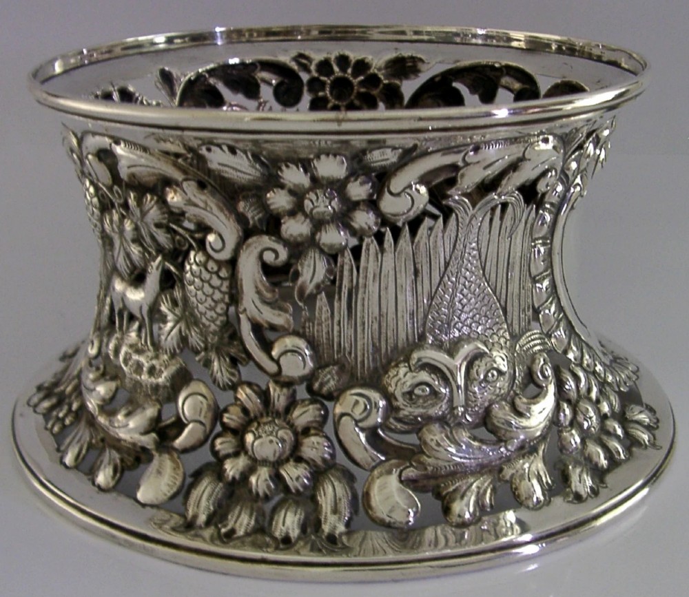 An hourglass-shaped sterling silver dish ring featuring intricately pierced fretwork with floral motifs, scrolls, and marine life details. View IV