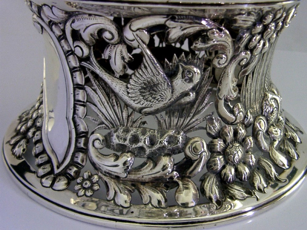 An hourglass-shaped sterling silver dish ring featuring intricately pierced fretwork with floral motifs, scrolls, and marine life details. View VII