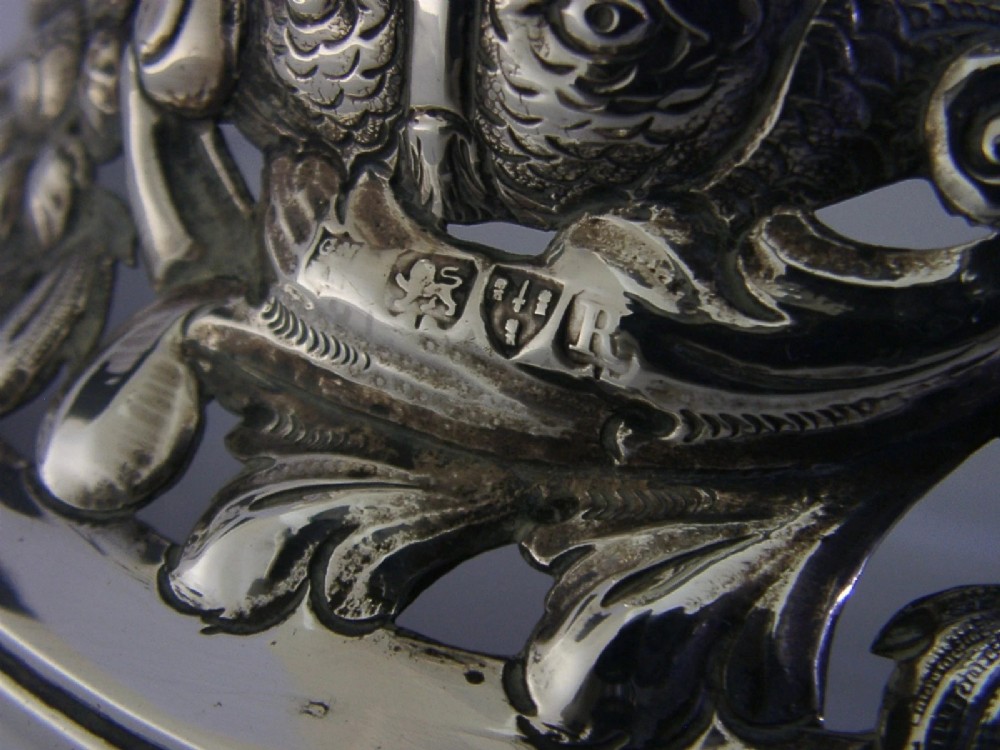 An hourglass-shaped sterling silver dish ring featuring intricately pierced fretwork with floral motifs, scrolls, and marine life details. View XI