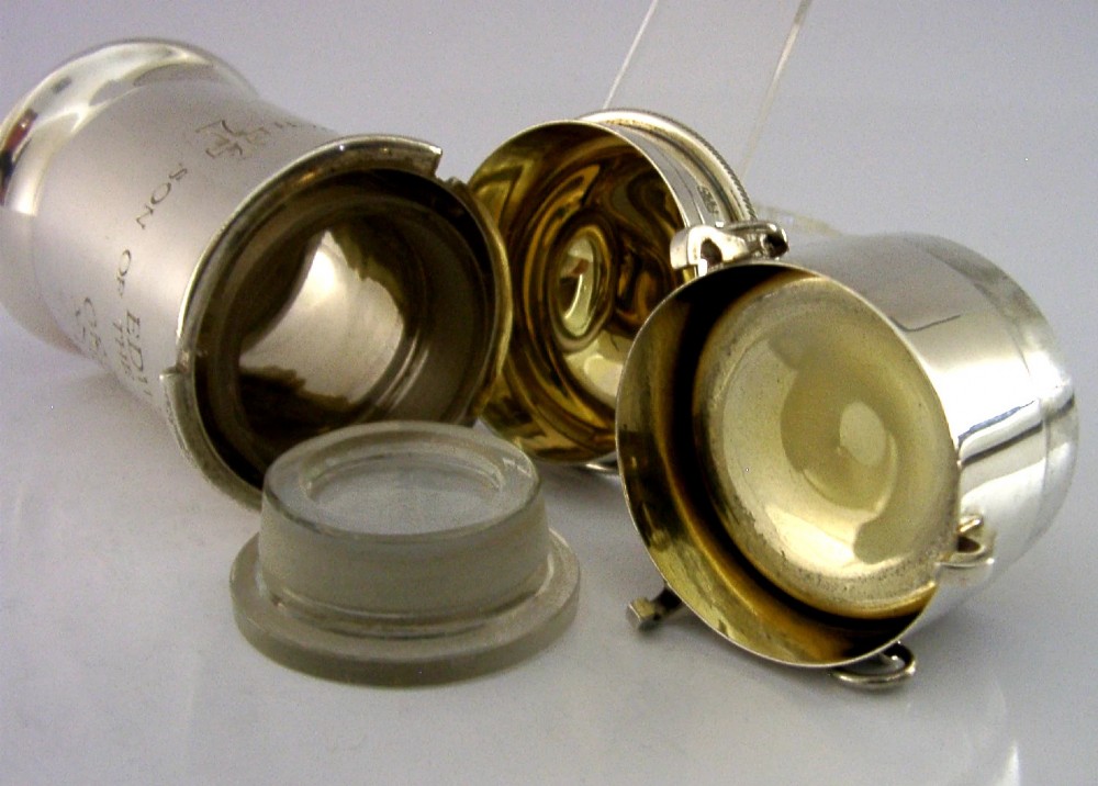 A cylindrical sterling silver pyx vessel with an engraved commemorative inscription, side suspension rings, and a fitted lid on a pedestal base. View VI