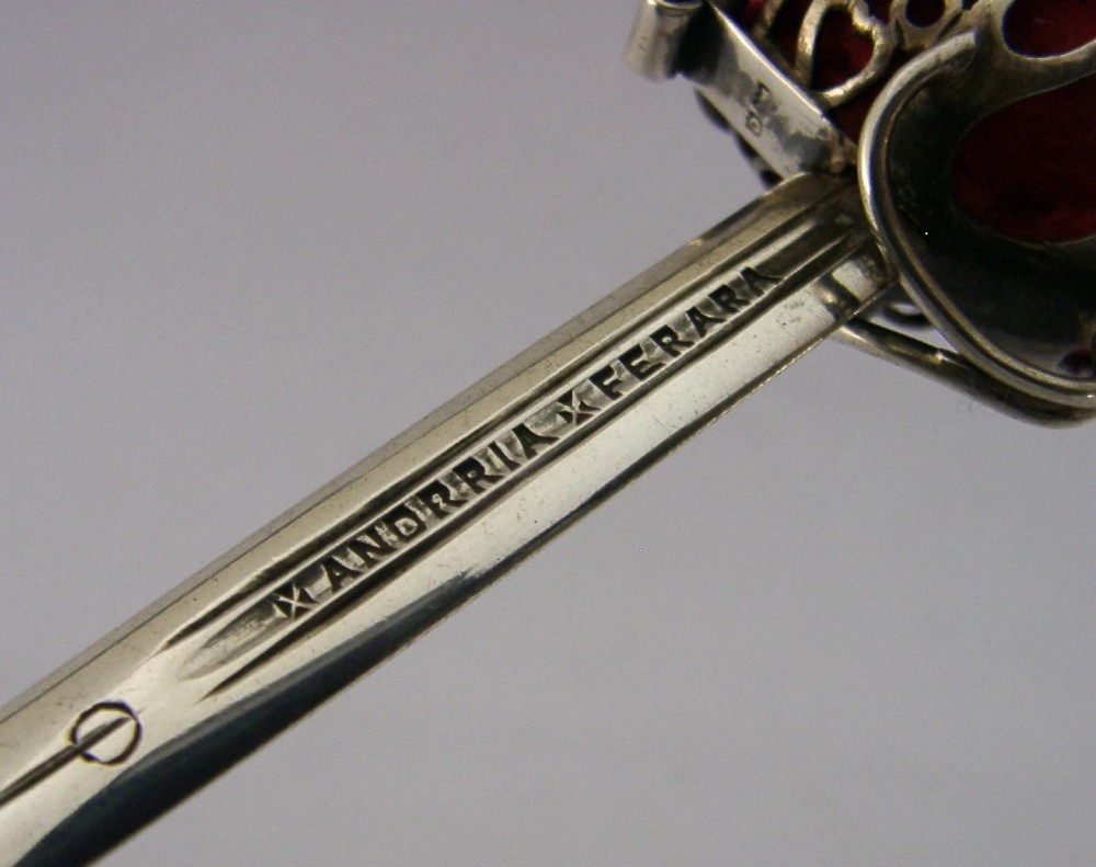 An Edwardian sterling silver letter opener featuring a smooth tapered blade stamped with British hallmarks and a decorative pierced finial housing a red orb. View III