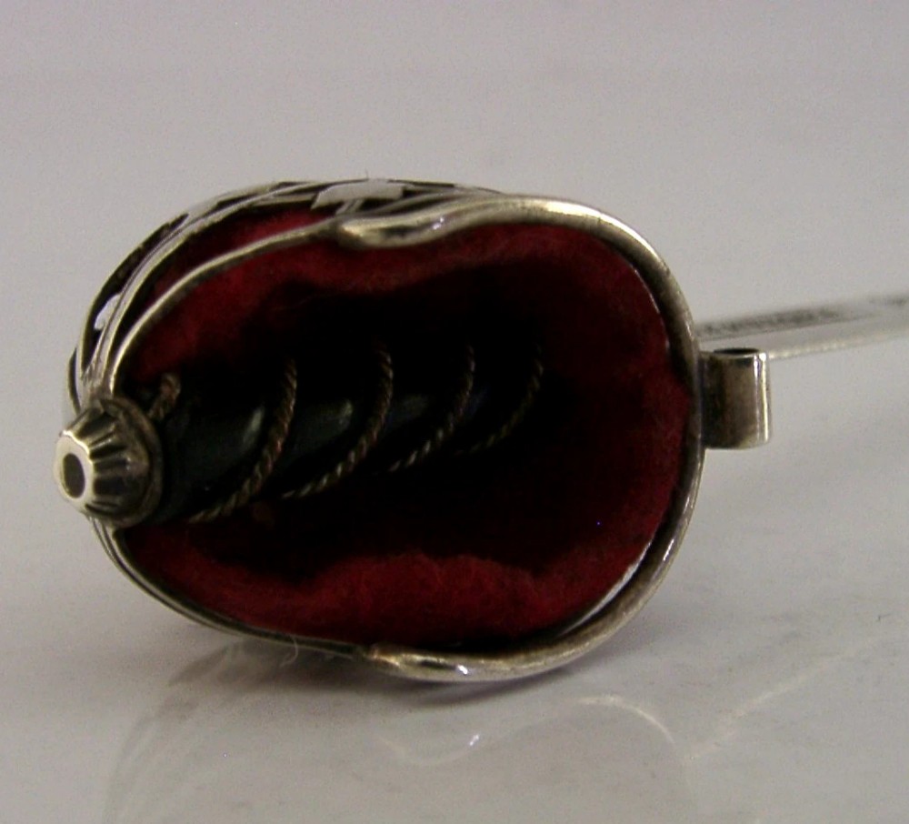An Edwardian sterling silver letter opener featuring a smooth tapered blade stamped with British hallmarks and a decorative pierced finial housing a red orb. View IV