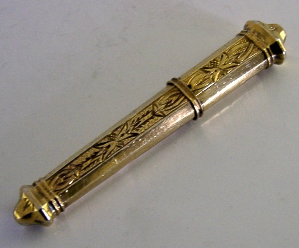 An antique French silver gilt needle case featuring engraved foliage and moulded finials.