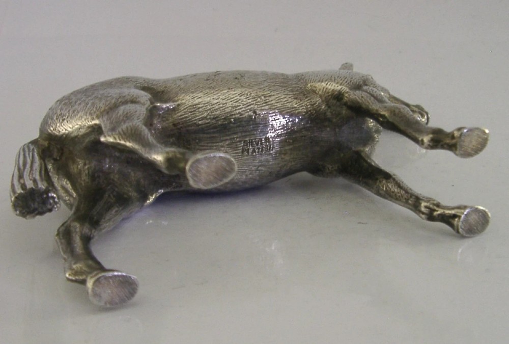 A silver-plated metal figure depicting a standing horse with detailed textured fur, erect ears, and a refined posture. View VI