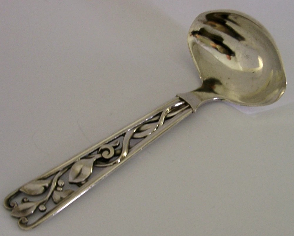 A Danish solid silver sauce ladle featuring a double-lipped deep bowl and an intricate openwork carved leaf handle.
