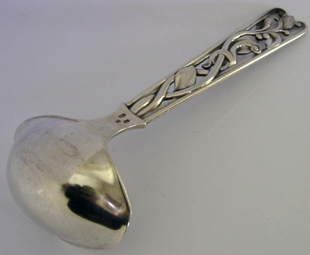 A Danish solid silver sauce ladle featuring a double-lipped deep bowl and an intricate openwork carved leaf handle. View V
