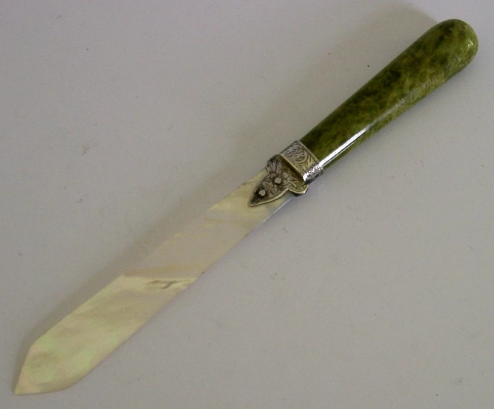An Edwardian letter opener featuring a polished green Connemara marble handle, an engraved sterling silver ferrule, and a tapered mother-of-pearl blade.