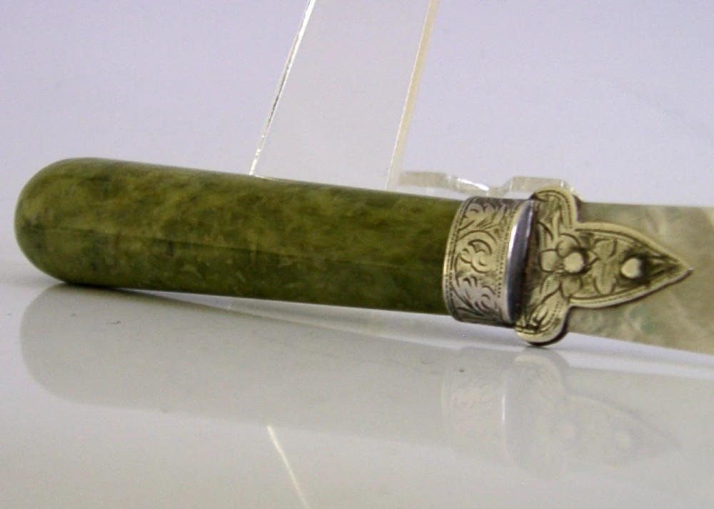 An Edwardian letter opener featuring a polished green Connemara marble handle, an engraved sterling silver ferrule, and a tapered mother-of-pearl blade. View IV
