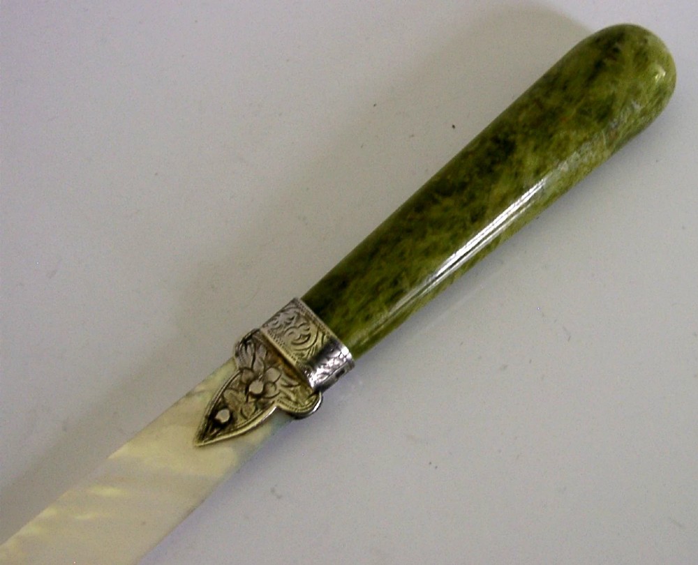 An Edwardian letter opener featuring a polished green Connemara marble handle, an engraved sterling silver ferrule, and a tapered mother-of-pearl blade. View V