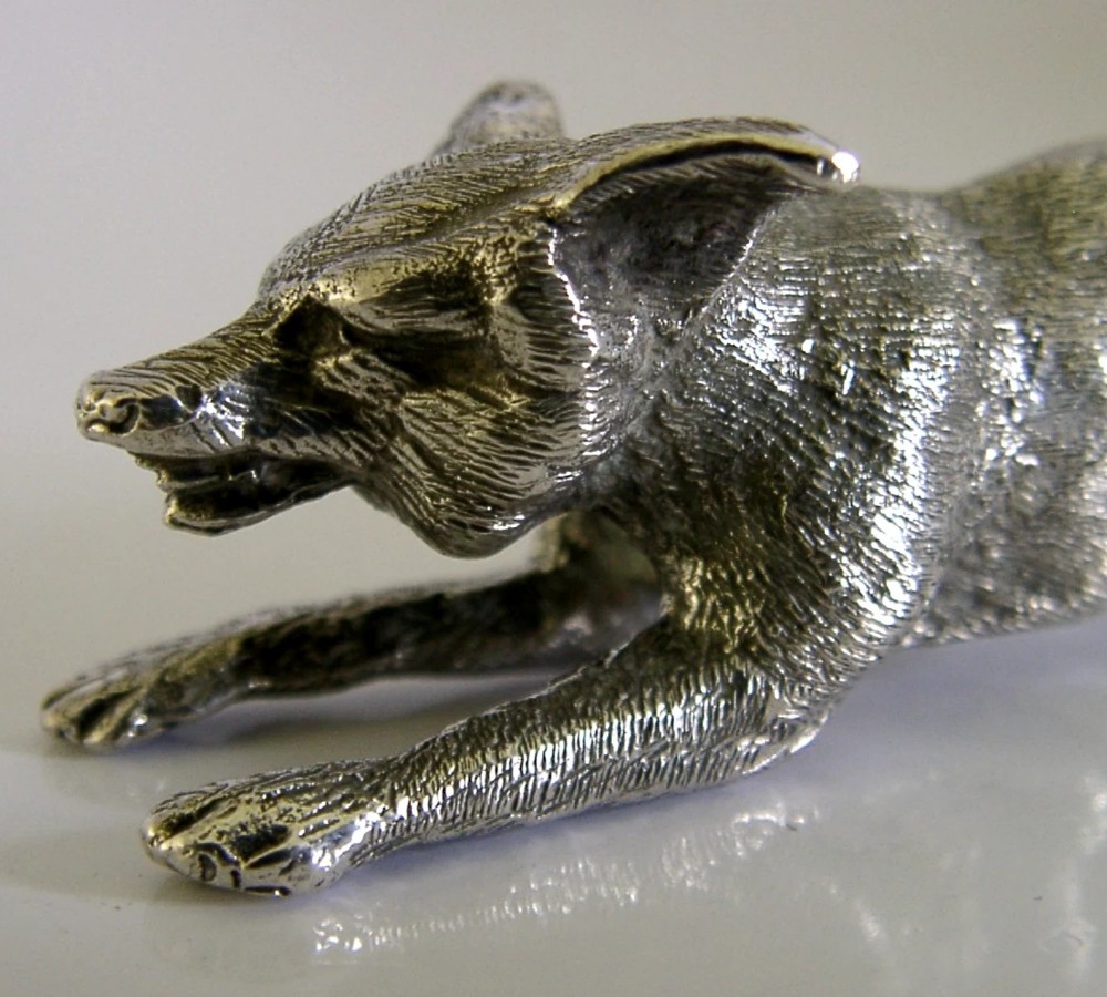 A solid sterling silver figurine depicting a fox in a low running pose with textured fur and detailed features. View III