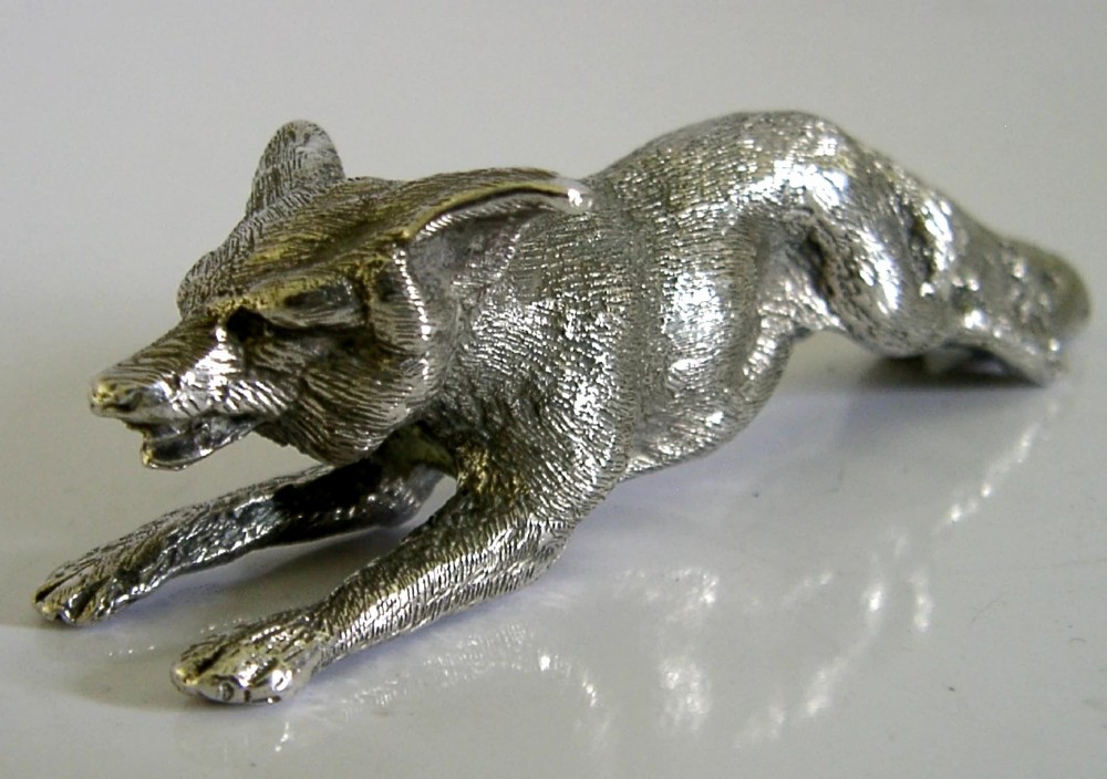 A solid sterling silver figurine depicting a fox in a low running pose with textured fur and detailed features. View IV