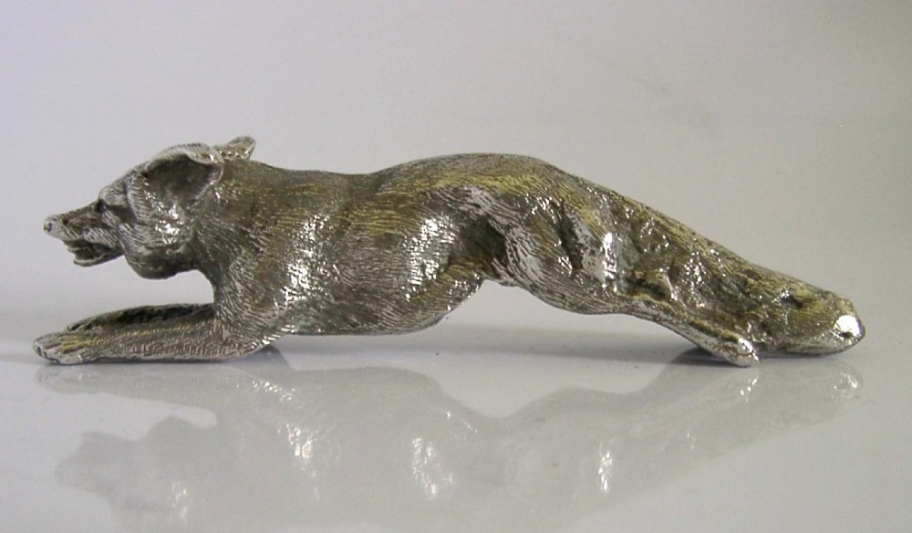 A solid sterling silver figurine depicting a fox in a low running pose with textured fur and detailed features. View V