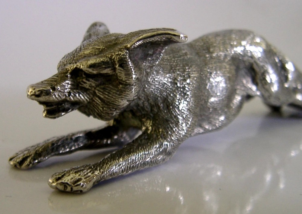 A solid sterling silver figurine depicting a fox in a low running pose with textured fur and detailed features. View VI