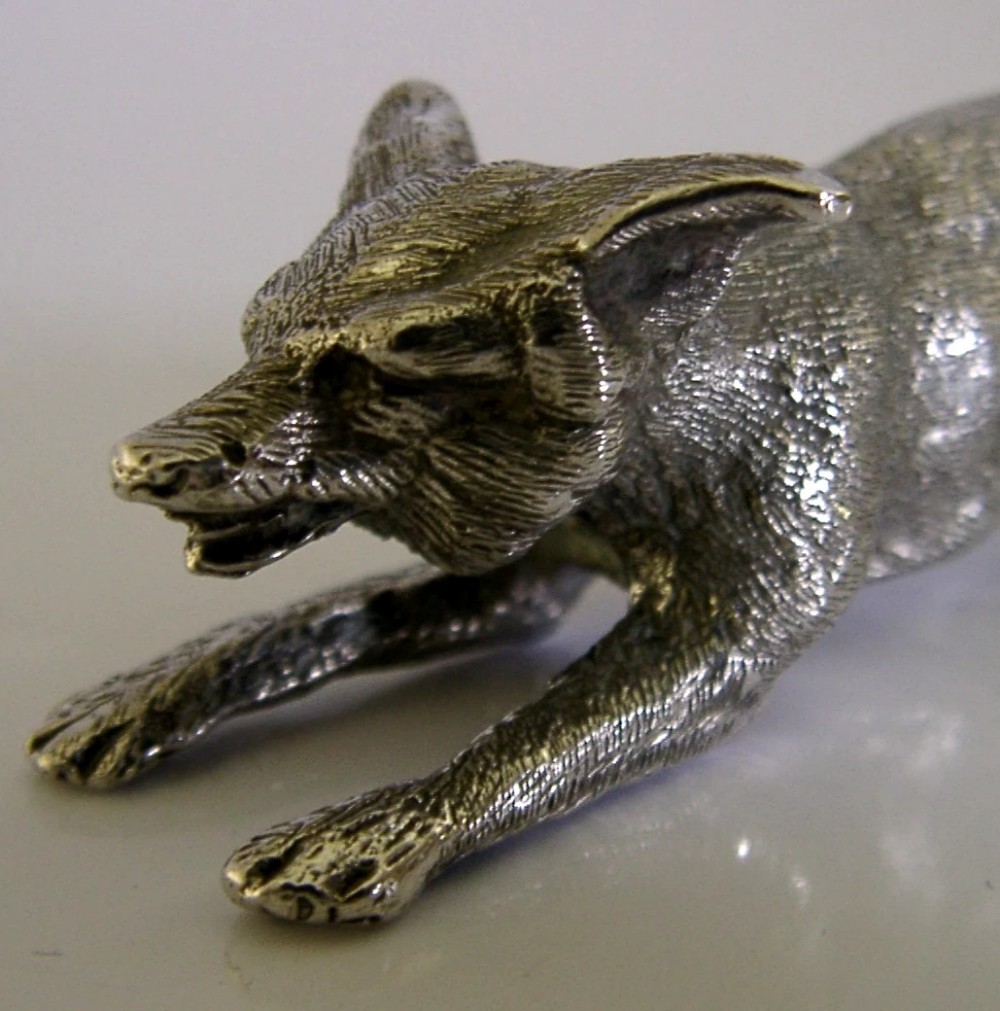 A solid sterling silver figurine depicting a fox in a low running pose with textured fur and detailed features. View VII