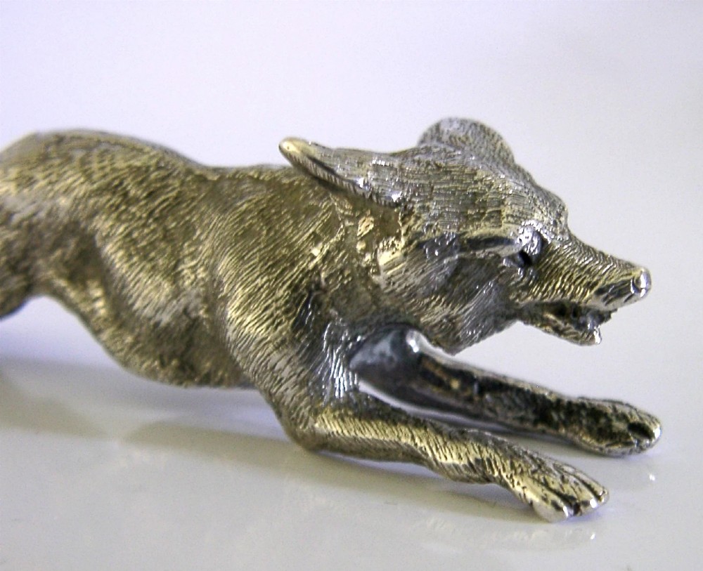 A solid sterling silver figurine depicting a fox in a low running pose with textured fur and detailed features. View VIII