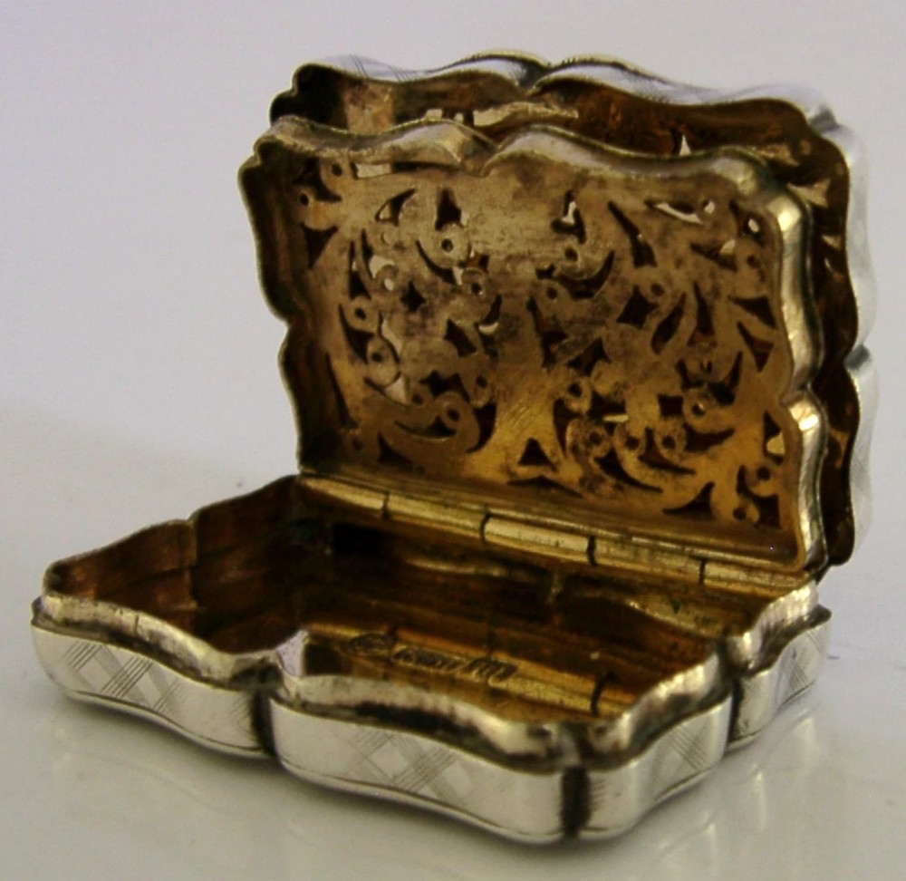 An open Victorian sterling silver vinaigrette box by Nathaniel Mills featuring a scalloped edge, cross-hatch engraving, and an internal hinged pierced gilt grill. View VII