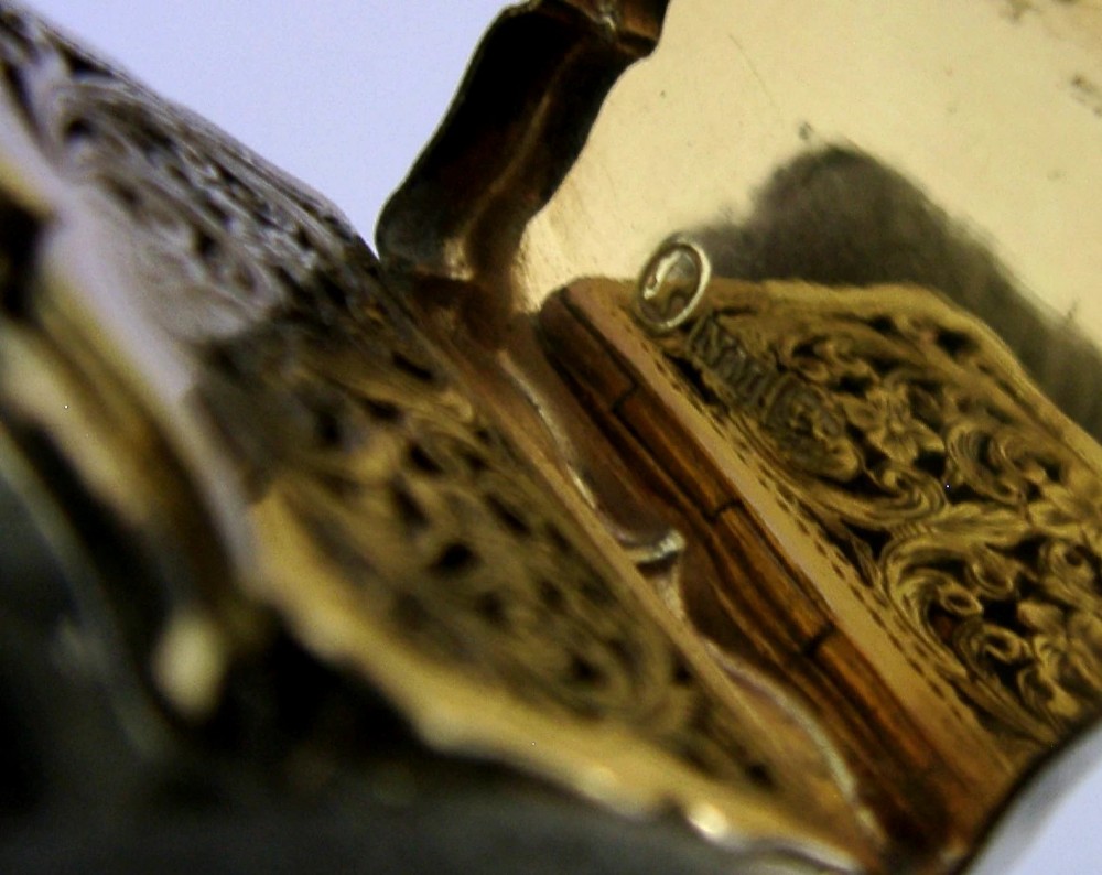 An open Victorian sterling silver vinaigrette box by Nathaniel Mills featuring a scalloped edge, cross-hatch engraving, and an internal hinged pierced gilt grill. View XI