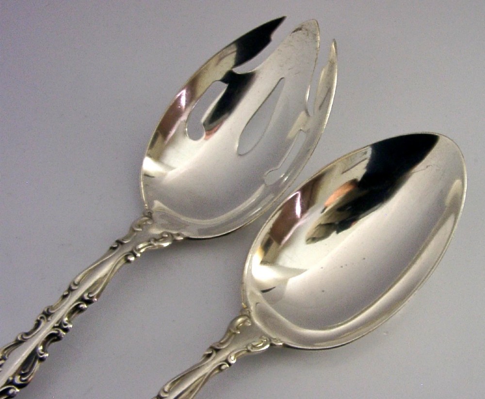 A pair of late Victorian solid sterling silver salad servers featuring ornate scroll edging and a pierced fork head alongside a matching spoon. View III
