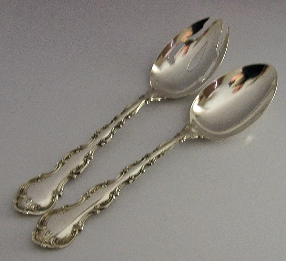 A pair of late Victorian solid sterling silver salad servers featuring ornate scroll edging and a pierced fork head alongside a matching spoon. View IV